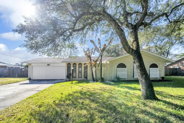 a front view of a house with a yard covered with trees