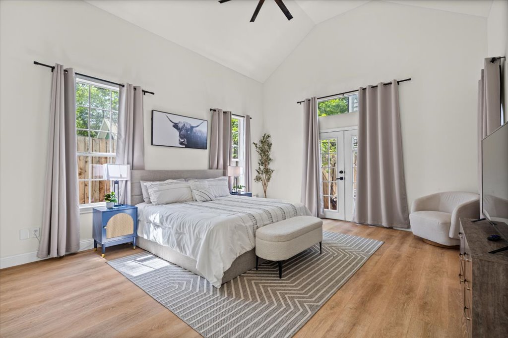 1201 Garden Street, Unit A Austin, TX 78702 - Photo 14 of 30 Vaulted ceiling bedroom featuring wood-finish flooring, multiple windows, and exterior double doors