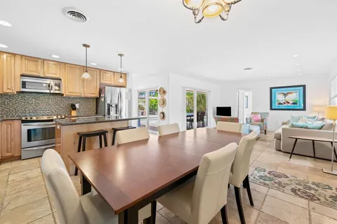 a large kitchen with a dining table chairs stainless steel appliances and cabinets