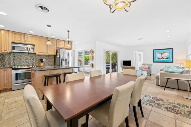 a large kitchen with a dining table chairs stainless steel appliances and cabinets