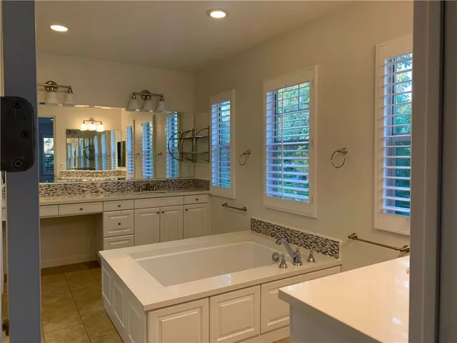 a bathroom with a tub sink and mirror