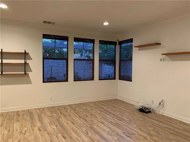 a view of an empty room with wooden floor and windows