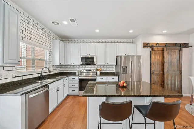 a kitchen with stainless steel appliances granite countertop a table chairs sink refrigerator and cabinets