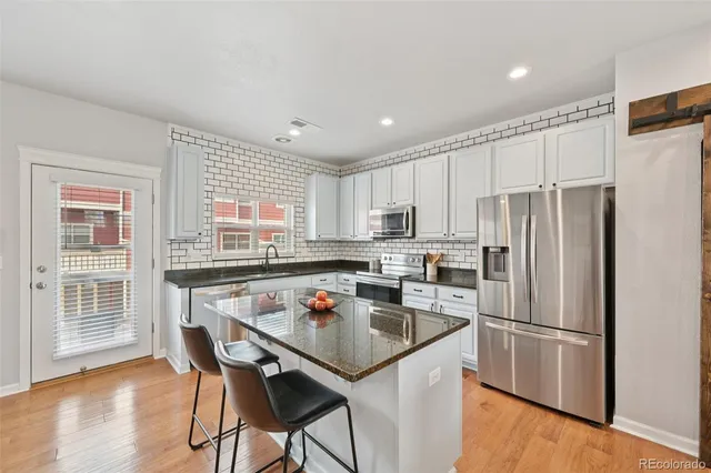 a kitchen with a refrigerator a stove a dining table and chairs