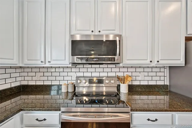 a kitchen with stainless steel appliances granite countertop white cabinets and a stove top oven