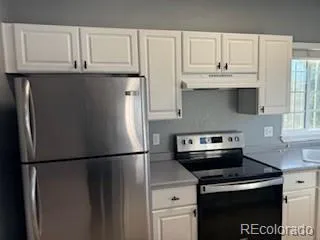 a kitchen with stainless steel appliances granite countertop a refrigerator a stove and a sink