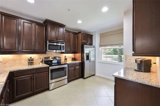 a kitchen with granite countertop wooden cabinets stainless steel appliances and a window