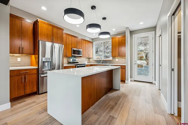 a kitchen with stainless steel appliances granite countertop a refrigerator a stove top oven a sink and dishwasher