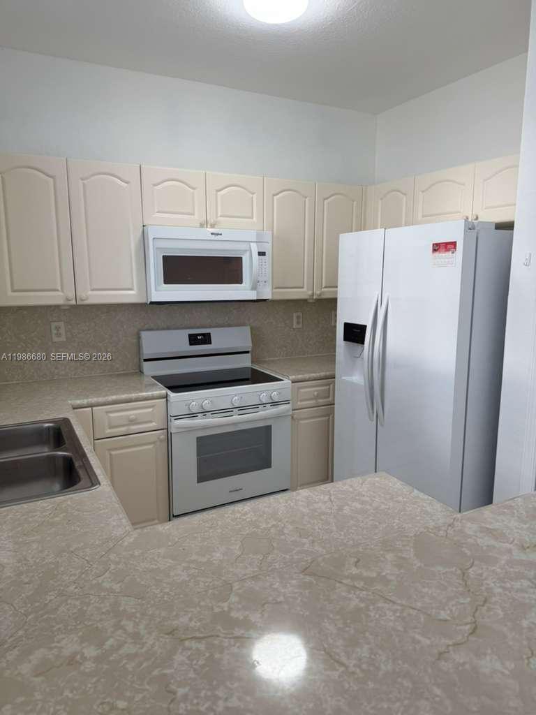 2470 Southeast 15th Place, Unit 335 Homestead, FL 33035 - Photo 3 of 33 a kitchen with a refrigerator sink and cabinets