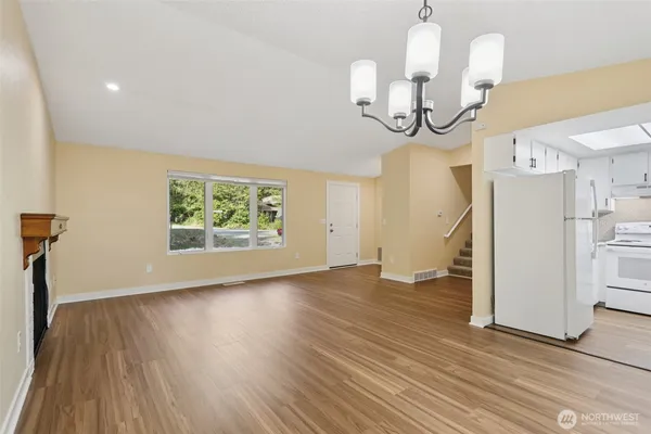 an empty room with wooden floor mirror and windows