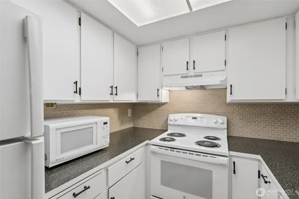 a kitchen with granite countertop white cabinets and white stove