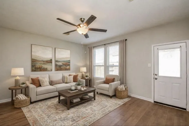 a view of a livingroom with a fireplace a ceiling fan and wooden floor