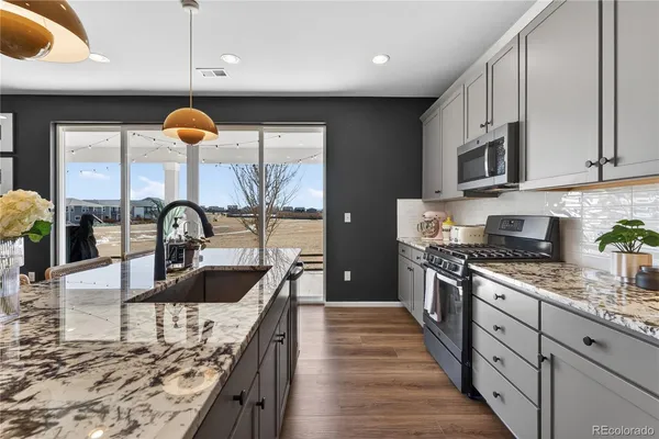 a kitchen with stainless steel appliances granite countertop a sink a stove and a wooden floors