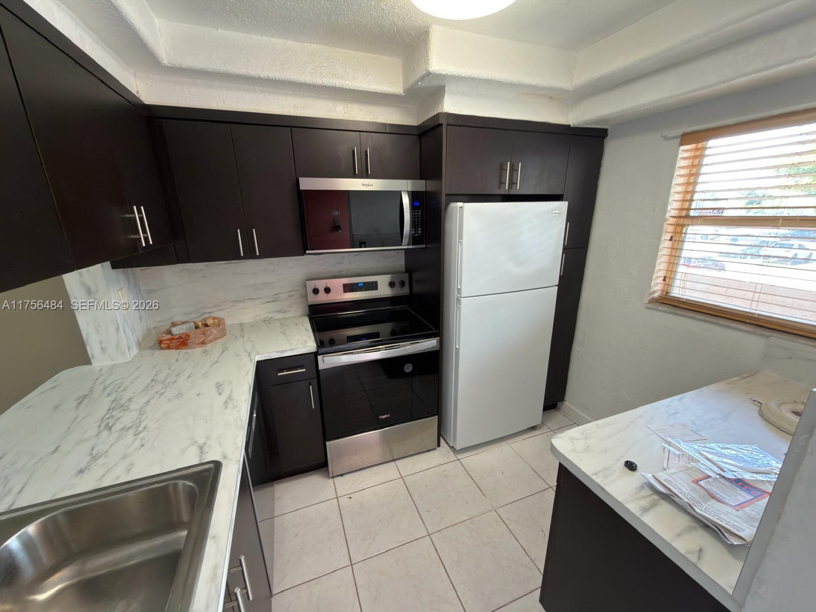 3400 Foxcroft Road, Unit 212 Miramar, FL 33025 - Photo 9 of 22 a kitchen with stainless steel appliances a refrigerator sink and microwave