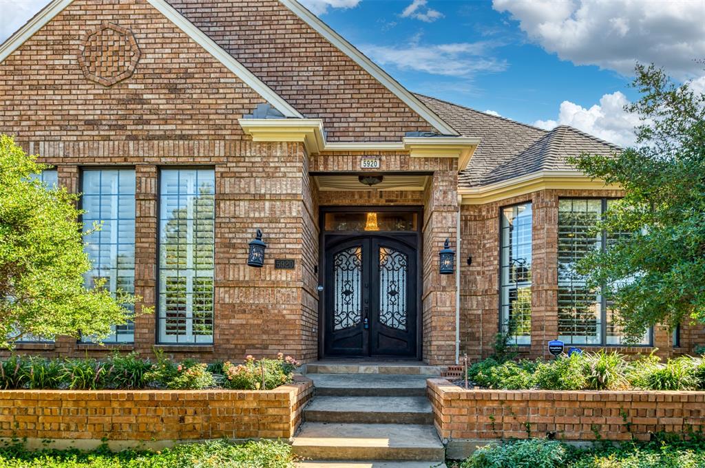 5920 Encore Drive Dallas, TX 75240 - Photo 2 of 34 Traditional brick exterior featuring a double entry door with decorative ironwork, tall windows with plantation shutters, a bay window, and a brick planter