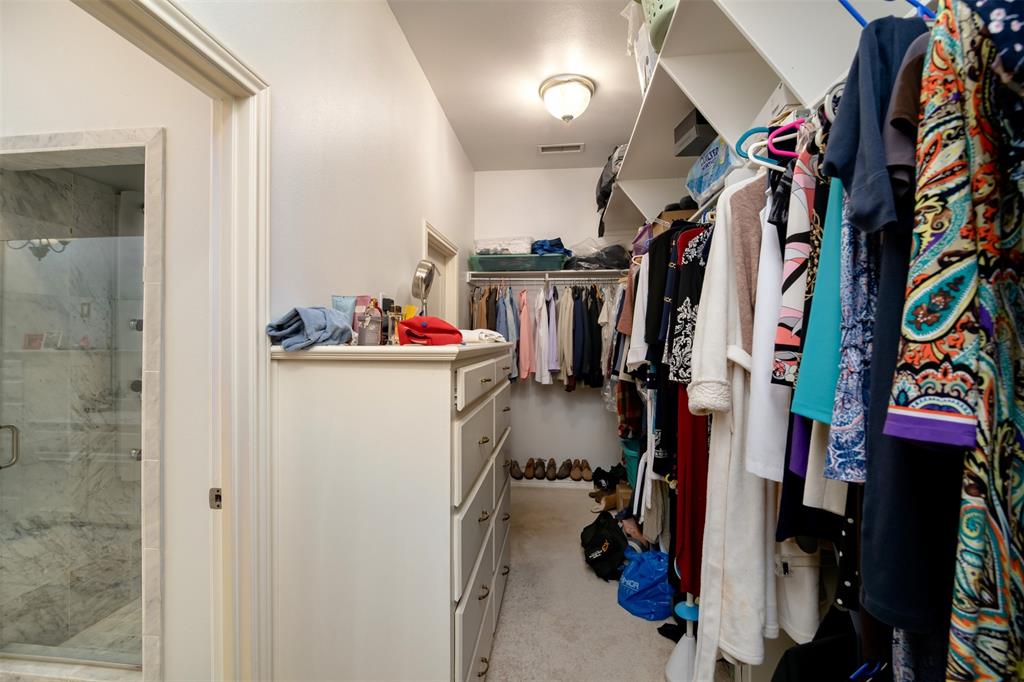 5920 Encore Drive Dallas, TX 75240 - Photo 21 of 34 Walk-in closet featuring extensive built-in shelving, multiple hanging rods, and a multi-drawer dresser unit