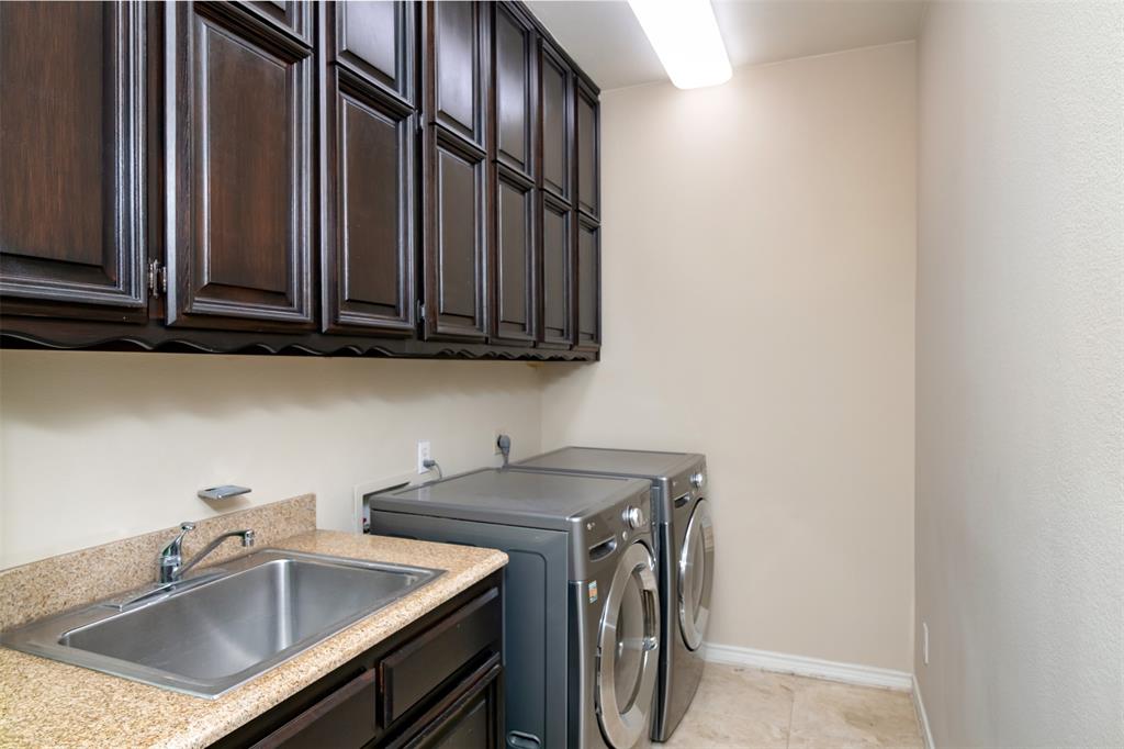 5920 Encore Drive Dallas, TX 75240 - Photo 22 of 34 Utility area featuring dark wood-finish cabinetry, a stainless steel sink with a chrome faucet, a speckled countertop, and neutral wall paint