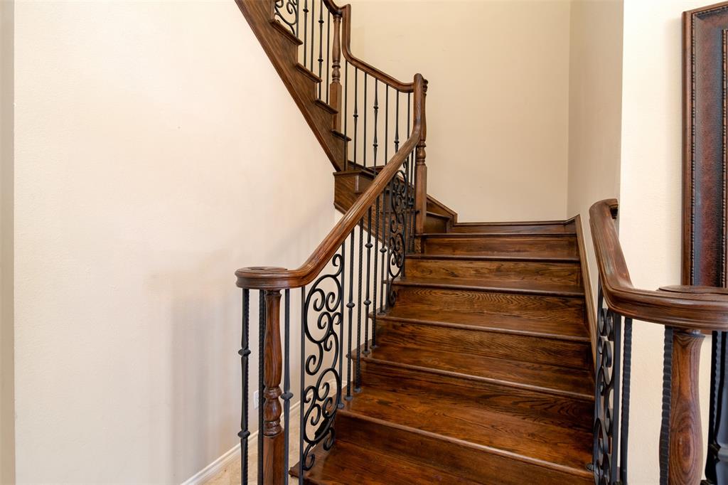 5920 Encore Drive Dallas, TX 75240 - Photo 24 of 34 Curved wood staircase featuring wrought iron balusters with ornate scrollwork and a substantial wood handrail