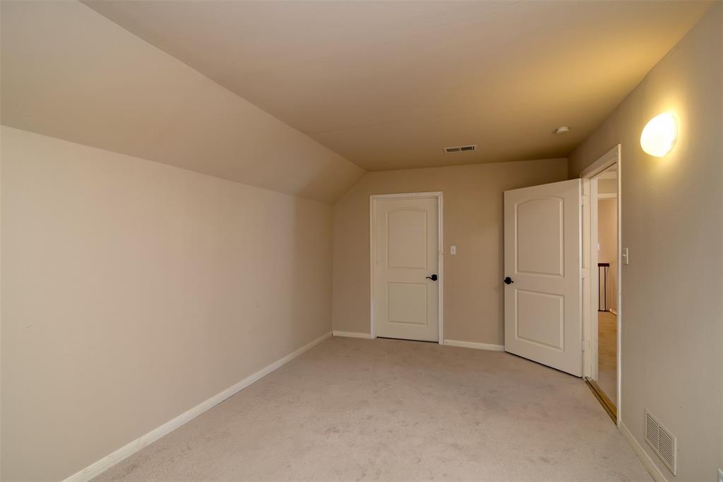 5920 Encore Drive Dallas, TX 75240 - Photo 31 of 34 Carpeted room featuring a sloped ceiling, light-colored walls, and two paneled doors with dark hardware