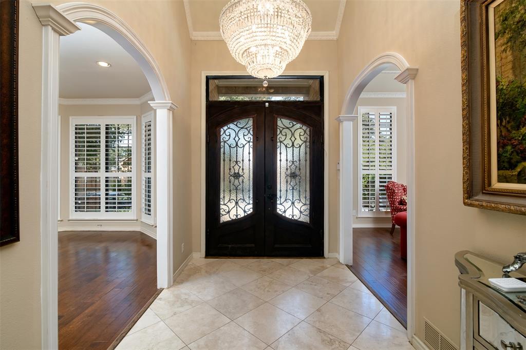 5920 Encore Drive Dallas, TX 75240 - Photo 4 of 34 Grand entryway featuring a large crystal chandelier, dark wood-finish double doors with ornate glass inserts, and light-toned tile flooring