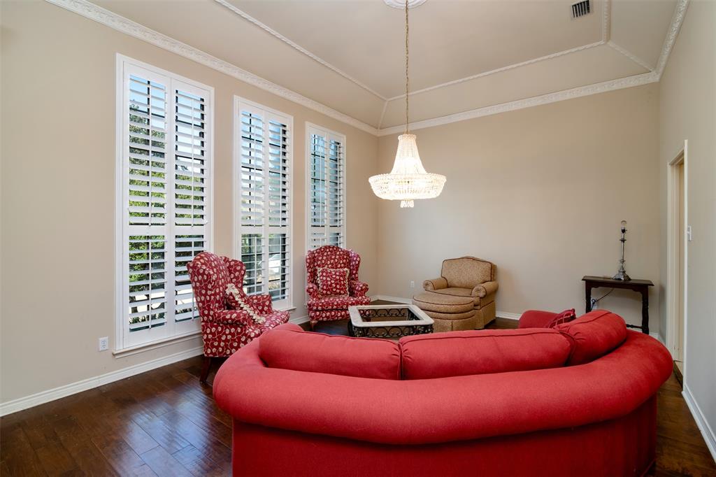 5920 Encore Drive Dallas, TX 75240 - Photo 7 of 34 Room featuring three tall windows with plantation shutters, wood-finish flooring, and a decorative ceiling with a central chandelier