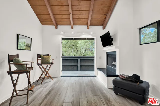 a living room with furniture a flat screen tv and a floor to ceiling window