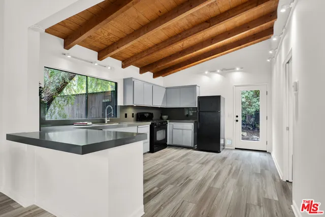 a kitchen with stainless steel appliances granite countertop a refrigerator a sink dishwasher a stove and white countertops with wooden floor