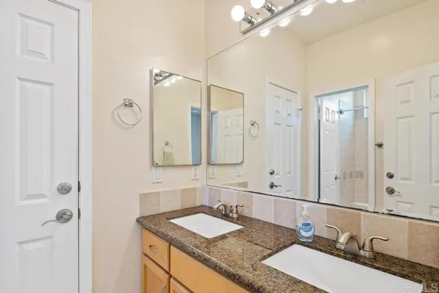 a bathroom with a granite countertop double vanity sink and mirror