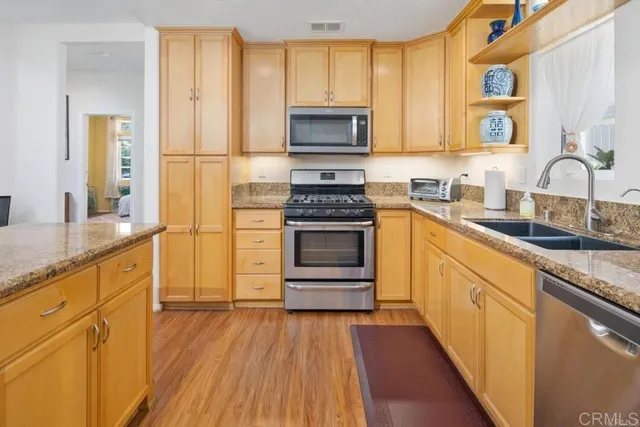 a kitchen with granite countertop wooden floors and stainless steel appliances