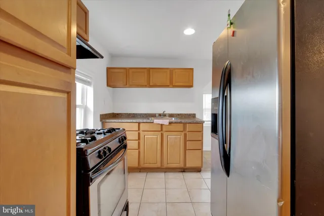 a kitchen with stainless steel appliances granite countertop a refrigerator a stove and a sink