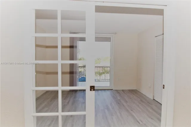 a view of an empty room with wooden floor and closet