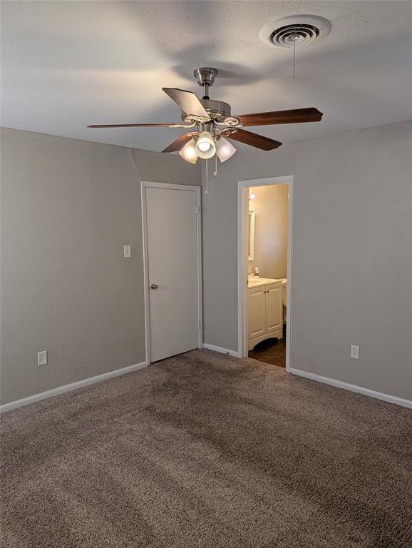 6324 Regal Road Forest Hill, TX 76119 - Photo 21 of 24 Unfurnished bedroom featuring dark carpet, ceiling fan, connected bathroom, and a textured ceiling