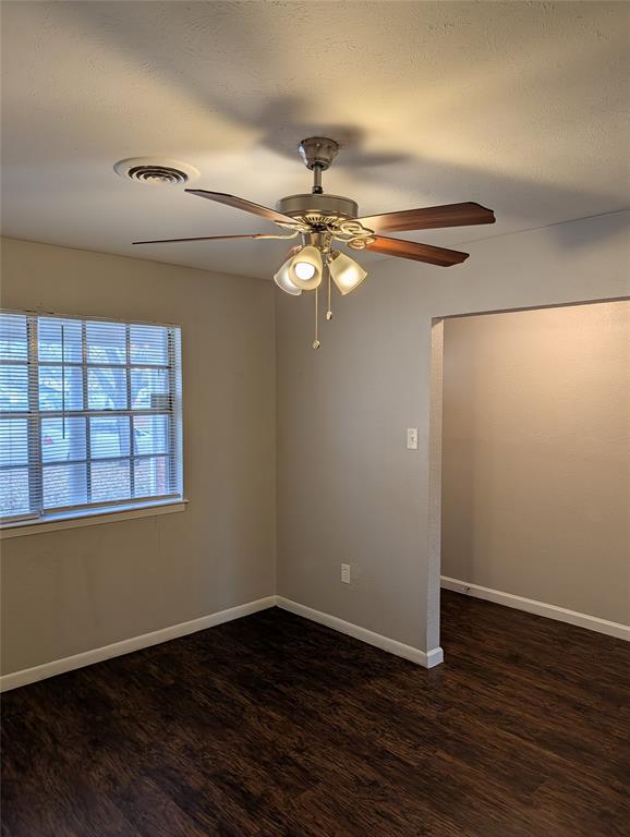 6324 Regal Road Forest Hill, TX 76119 - Photo 7 of 24 Unfurnished room with ceiling fan, dark wood-style flooring, and a textured ceiling