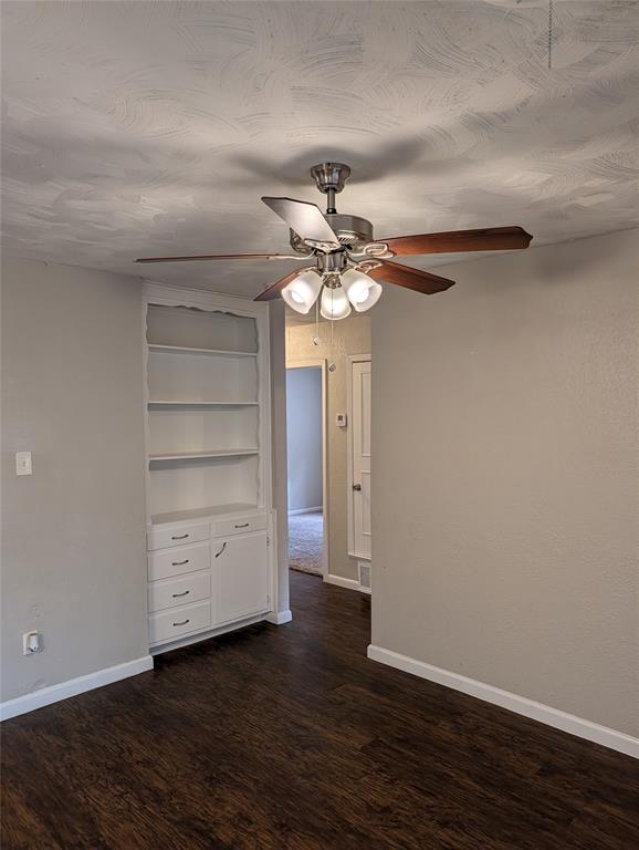 6324 Regal Road Forest Hill, TX 76119 - Photo 8 of 24 Empty room featuring built in shelves, dark wood-type flooring, and ceiling fan