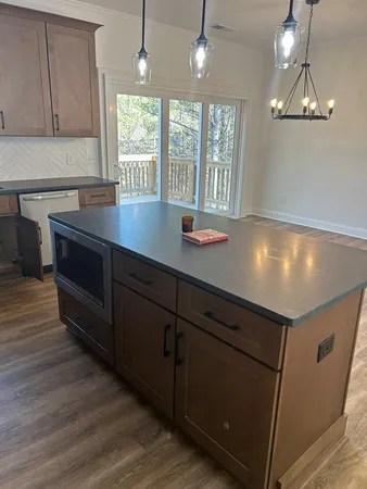 a kitchen with kitchen island granite countertop a stove a sink and wooden floors