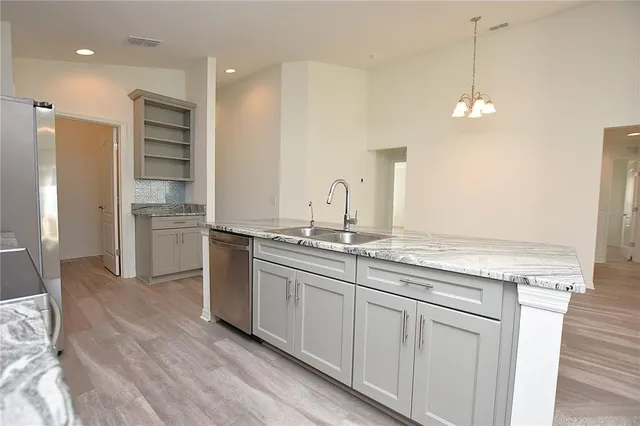a kitchen with granite countertop kitchen island a sink stainless steel appliances and wooden floor