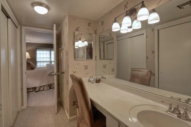 a bathroom with a sink a large mirror and a light fixture