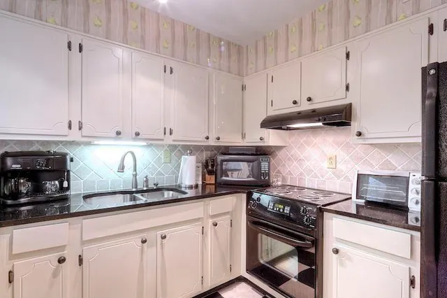 a kitchen with stainless steel appliances granite countertop a sink a stove and cabinets