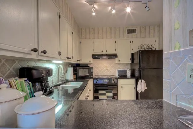 a kitchen with stainless steel appliances granite countertop a refrigerator a stove and a sink