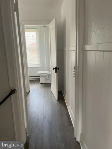 a view of a hallway with wooden floor and a bathroom