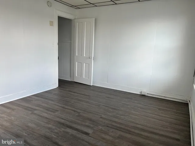 a view of an empty room with wooden floor and closet