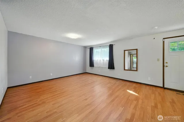 a view of an empty room with wooden floor and windows