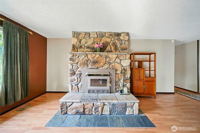 a living room with stainless steel appliances furniture a fireplace and wooden floor