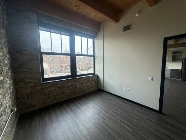 an empty room with wooden floor and windows