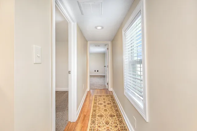 a view of a hallway with wooden floor and a bathroom