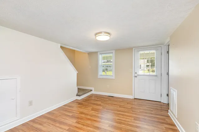 a view of an empty room with wooden floor and a window