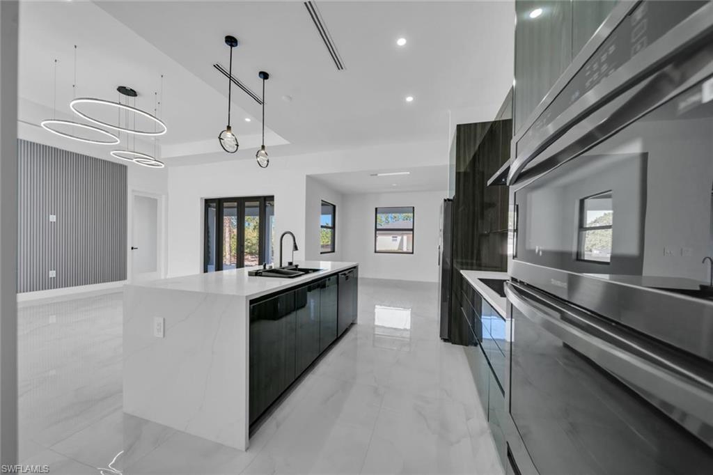 3312 17th Street Southwest Lehigh Acres, FL 33976 - Photo 5 of 12 a large kitchen with stainless steel appliances a large counter top a stove and a refrigerator