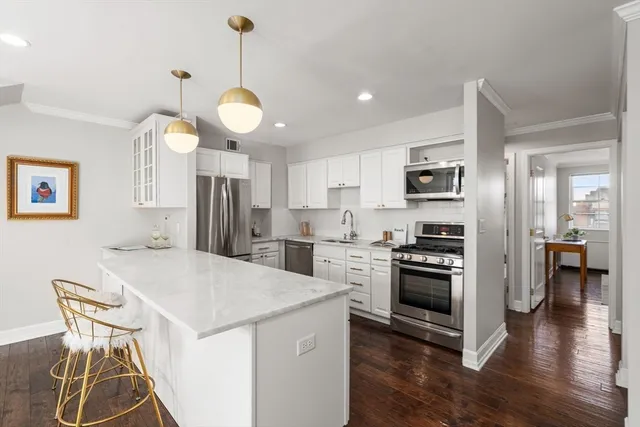 a kitchen that has a table chairs stainless steel appliances and wooden floor
