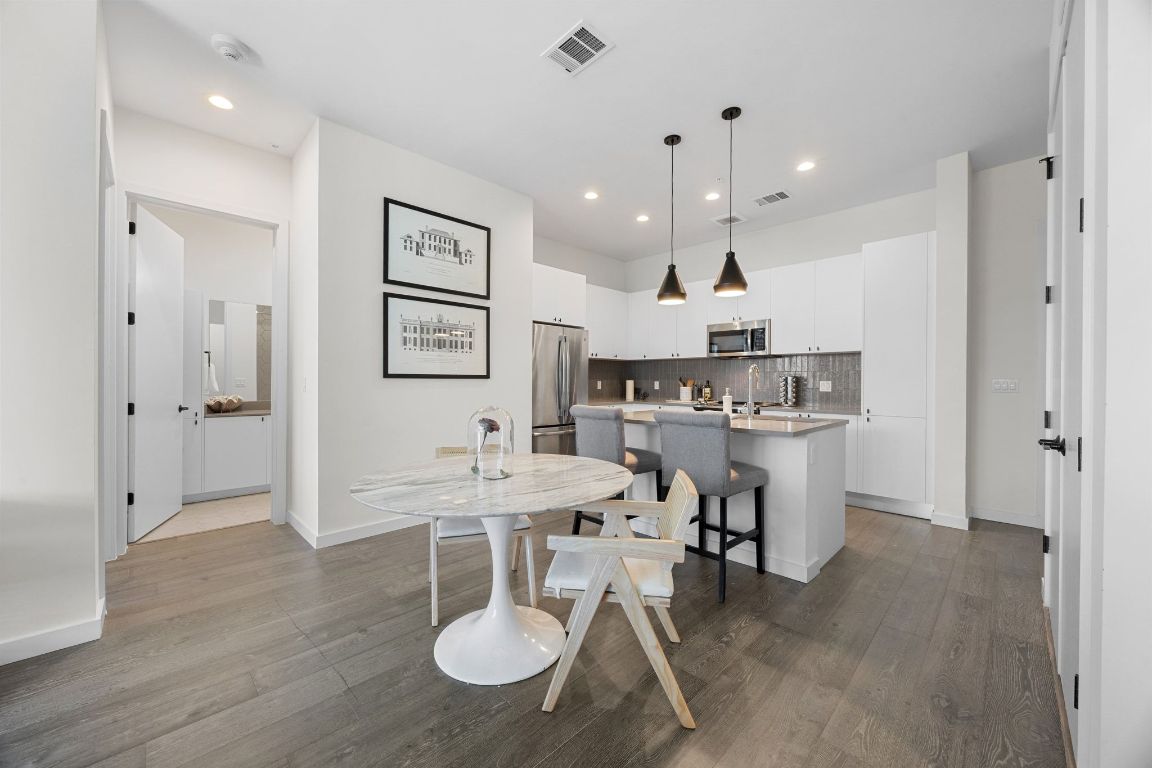 800 Embassy Drive, Unit 229 Austin, TX 78702 - Photo 7 of 40 a kitchen with stainless steel appliances granite countertop a dining table chairs and white cabinets