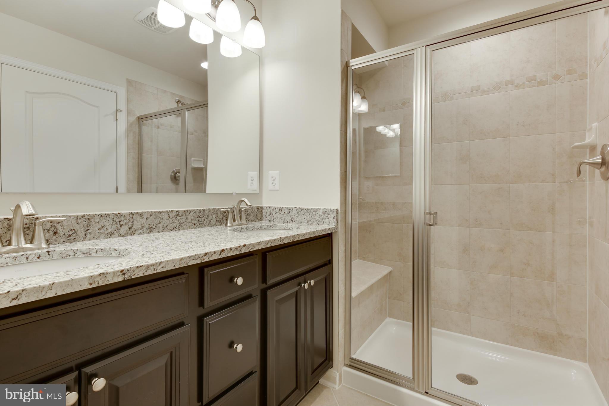 7240 Brinley Way Hanover, MD 21076 - Photo 19 of 22 a bathroom with a granite countertop sink a mirror and a shower